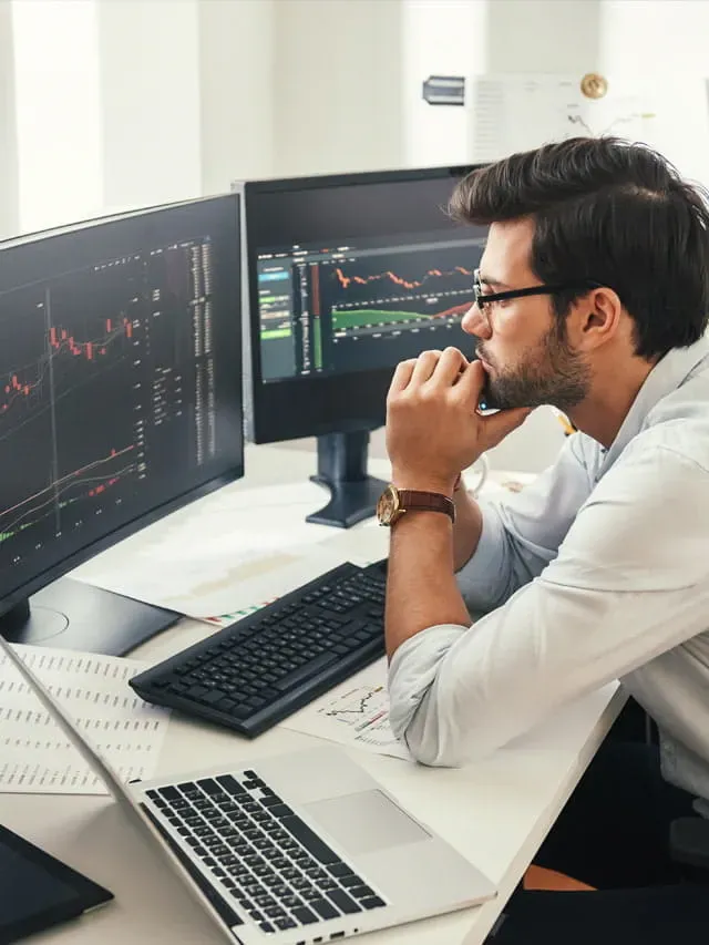 Day trader looking at two computer screens with charts
